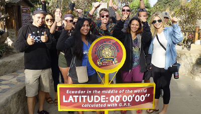 Students in Ecuador at sign claiming the GPS-calculated middle of the world
